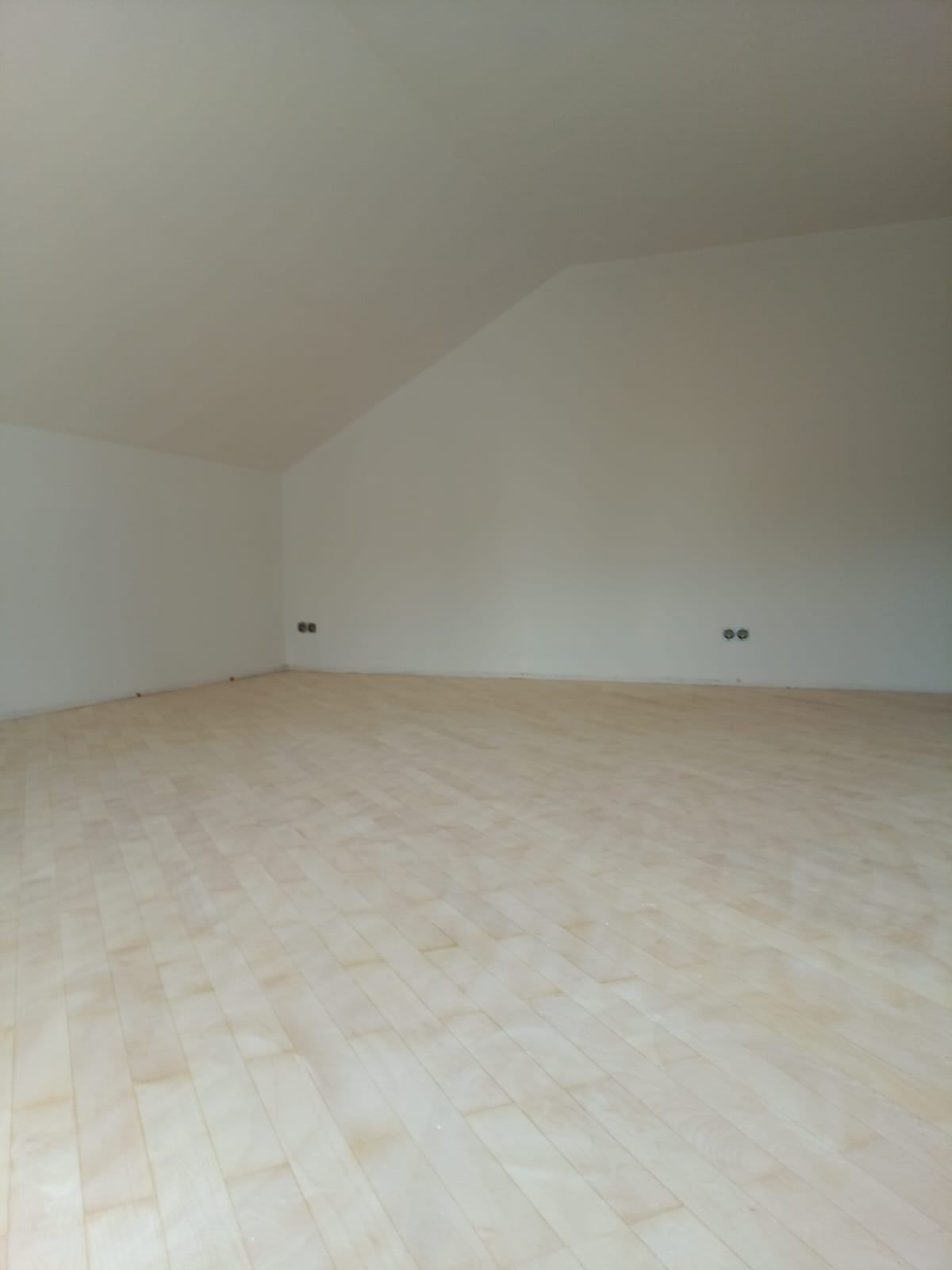 Fertig renovierter Dachgeschossraum mit weißen Wänden und neuer Decke