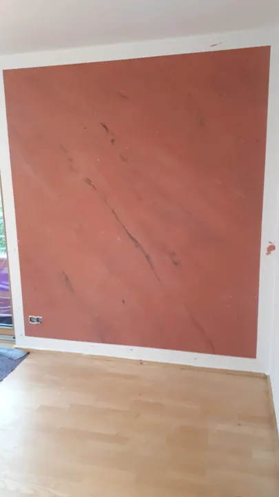 Terrakottafarbene Wand mit lebendiger Spachtelstruktur und weißem Rand