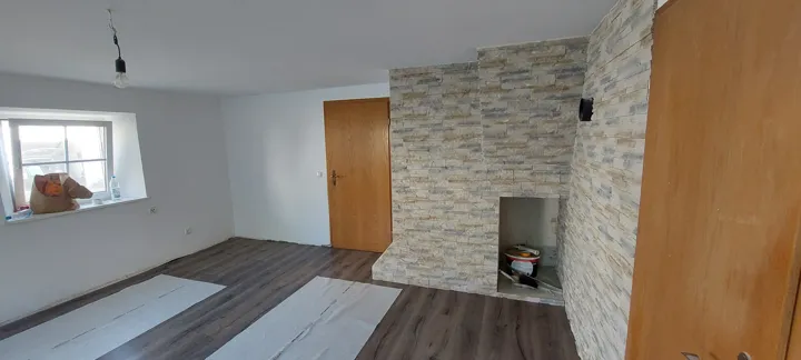 Renovierter Wohnraum mit heller Steinoptik an der Kaminverkleidung und angrenzender Wand