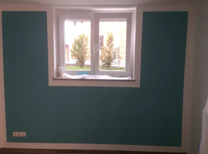 Petrolfarbene Wand mit weiß eingefasstem Fenster