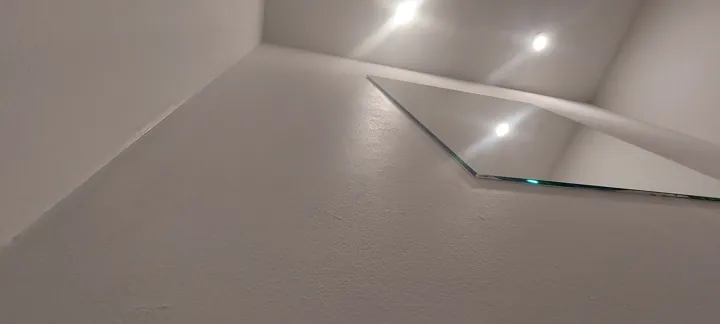 Weiß gestaltetes Treppenhaus mit Glasgeländer und eingelassenen Deckenspots