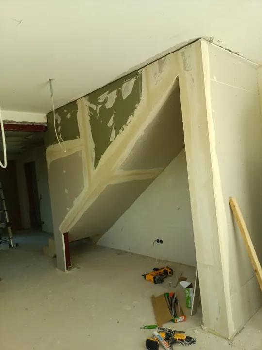 Verspachtelte weiße Trockenbauverkleidung unter einer Treppe