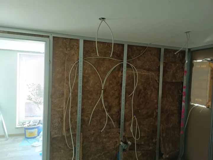 Offene Metallständerwand mit brauner Dämmung und vorbereiteten Leitungen
