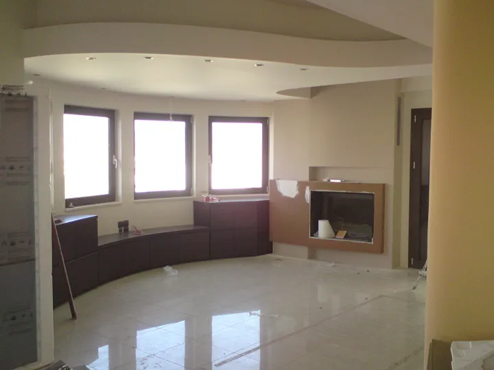 Heller Wohnraum mit Kaminverkleidung, dunklen Wandakzenten und abgestufter Decke